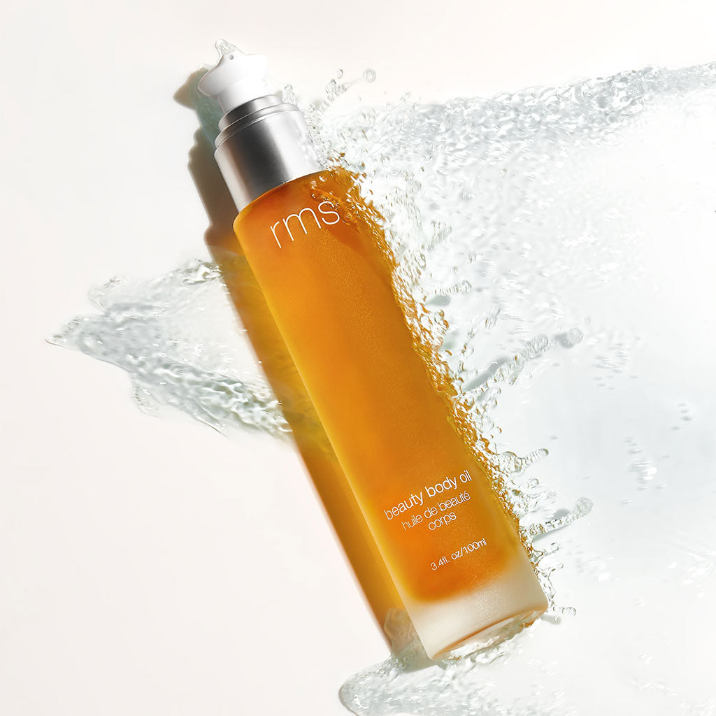 Glass bottle of RMS Beauty Body Oil with a pump dispenser, showing a lightweight, golden-hued oil designed to hydrate and nourish the skin