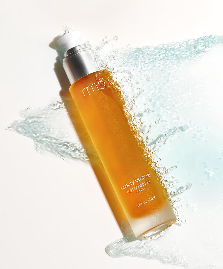 Glass bottle of RMS Beauty Body Oil with a pump dispenser, showing a lightweight, golden-hued oil designed to hydrate and nourish the skin